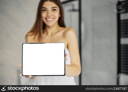 young woman holding blank tablet bathroom