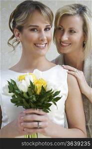 Young woman holding bouquet, mother standing by