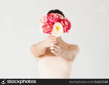 young woman holding bouquet of flowers over her face.