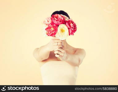 young woman holding bouquet of flowers over her face