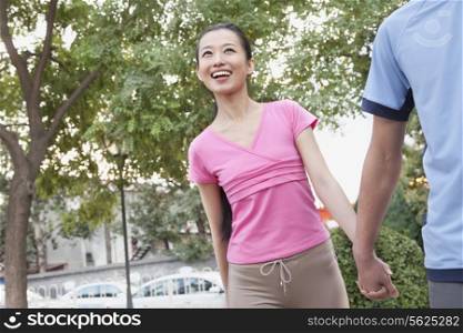 Young Woman Holding Boyfriend&rsquo;s Hand In Park