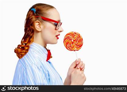Young woman holding candy. Image of young funny woman in red glasses holding candy