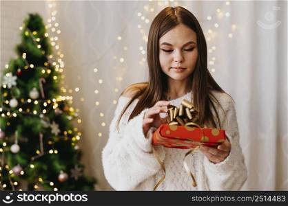 young woman holding christmas tree indoors