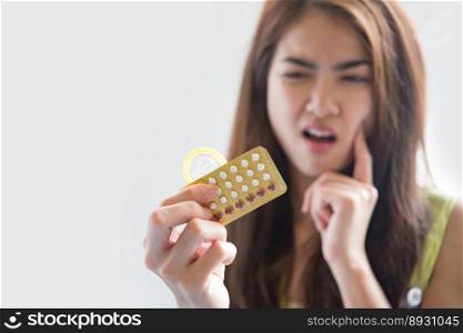 Young woman holding condom and contraceptive pills prevent pregnancy