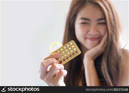 Young woman holding condom and contraceptive pills prevent pregnancy