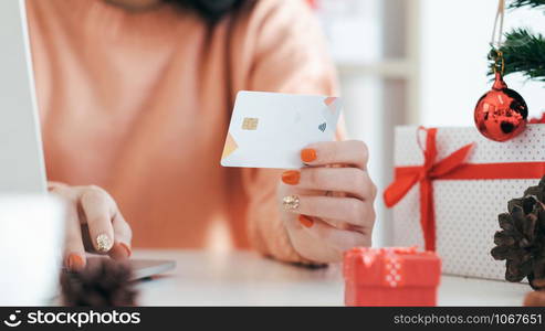 Young woman holding credit card and doing shopping online. New year, Christmas gift shopping.