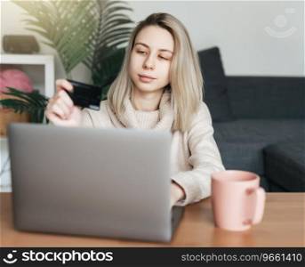 Young woman holding credit card and using laptop computer. Girl working online. Online shopping,  internet banking,  working from home 