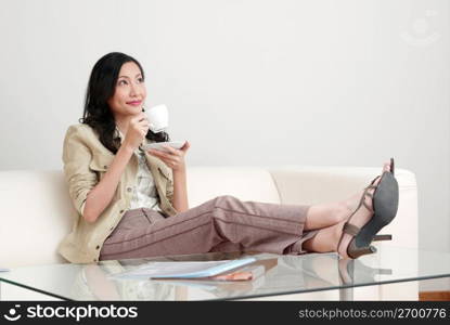 Young woman holding cup and saucer, contemplating