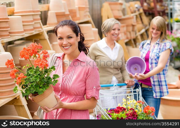 Young woman holding geranium in clay pot at garden centre