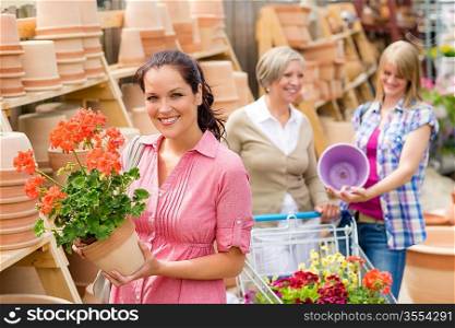 Young woman holding geranium in clay pot at garden centre
