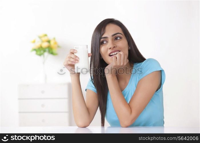 Young woman holding glass of milk at home