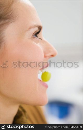 Young woman holding grape in mouth