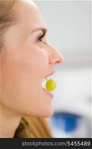 Young woman holding grape in mouth