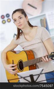 young woman holding guitar and learning to play song