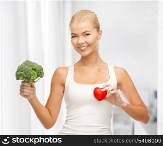 young woman holding heart symbol and broccoli