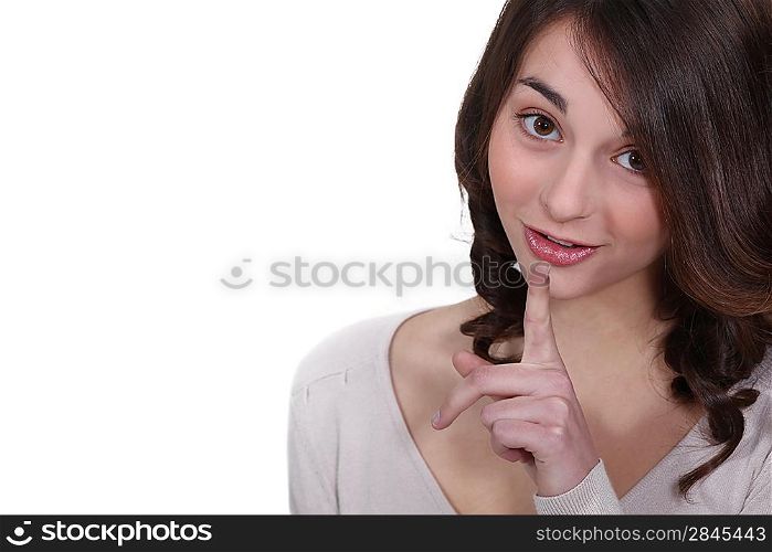 Young woman holding her index finger up to her lips