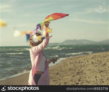Young Woman holding kite at beach on autumn day. Beautiful Young Woman Holding A Kite at Beach on autumn day colored filter