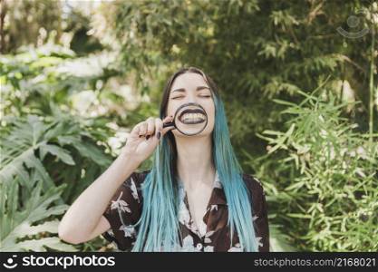 young woman holding magnifying glass front her mouth