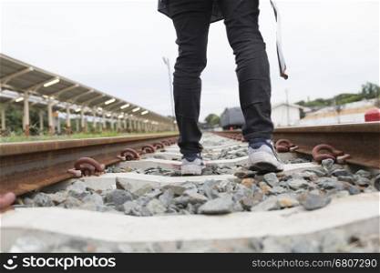 young woman holding map with backpack walking on railway at train station - travel concept