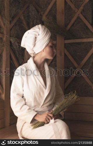 young woman holding medical herbs relaxing sauna