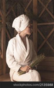 young woman holding medical herbs relaxing sauna