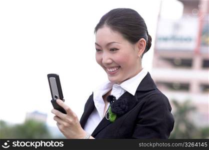 Young woman holding mobile phone, smiling