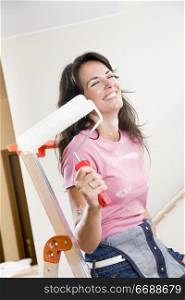 Young woman holding paint roller and smiling