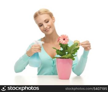 young woman holding pot with flower and spray bottle