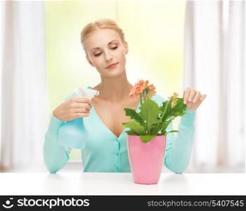 young woman holding pot with flower and spray bottle