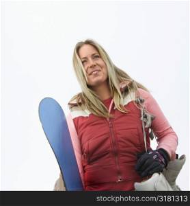 Young woman holding snowboard and boots.