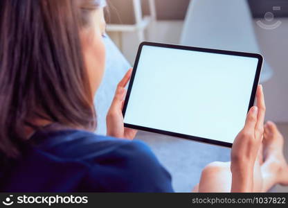 Young woman holding tablet with blank screen on the sofa in house.
