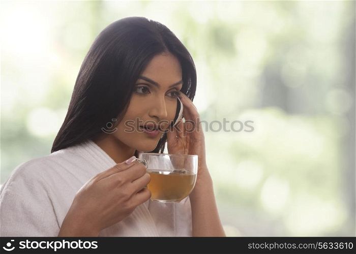 Young woman holding tea cup while on call