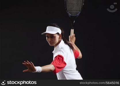 Young woman holding tennis racket isolated over black background