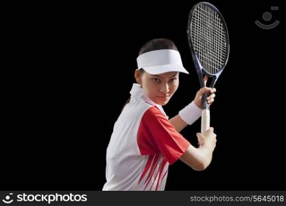 Young woman holding tennis racket isolated over black background