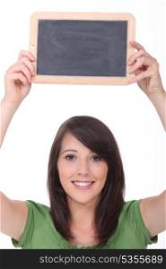 Young woman holding up a small blank blackboard
