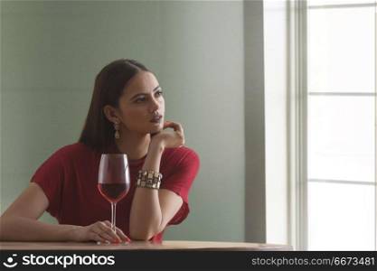 Young woman holding wine glass sitting at table