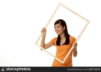 Young woman holding wooden frame, portrait