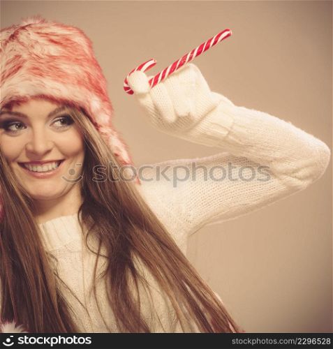 Young woman holding xmas mug with candy cane. Girls hands in woolen white gloves. Christmas time concept.. Girl playing with cane.