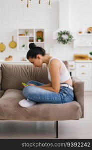 Young woman holds a smartphone in her hands, hunched over sitting on the couch