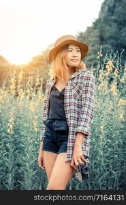 Young woman holds retro style camera in her hand while traveling in outdoor nature landscape in summer.