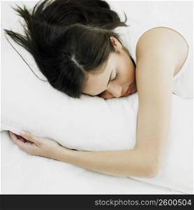 Young woman hugging a pillow on the bed and sleeping