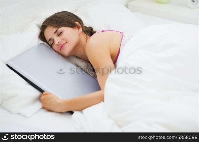 Young woman hugging laptop while sleeping