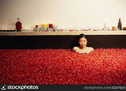 Young woman in a bathtub full of rose petals