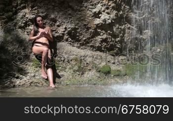 young woman in a bikini by the waterfall