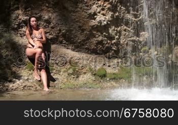 young woman in a bikini by the waterfall