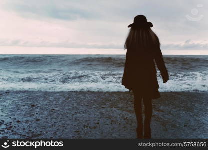 young woman in a black coat on the beach
