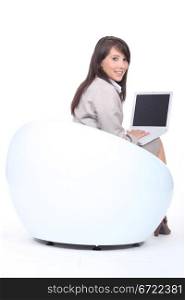 Young woman in a funky white chair, using a laptop computer