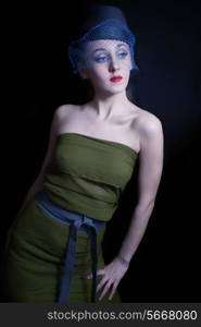 young woman in a green dress and hat veils on black background