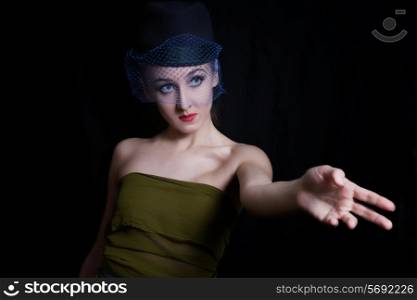 young woman in a green dress and hat veils on black background