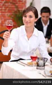 Young woman in a restaurant raising a glass of rose wine